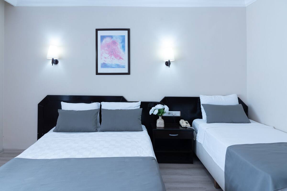 A modern hotel room with two beds, a nightstand with a phone, and a framed picture on the wall.
