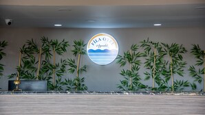 A reception area with a circular sign reading "FILA HOTEL Aylaç" and bamboo plants. - FİLA OTEL AYVALIK (Ayvalik)