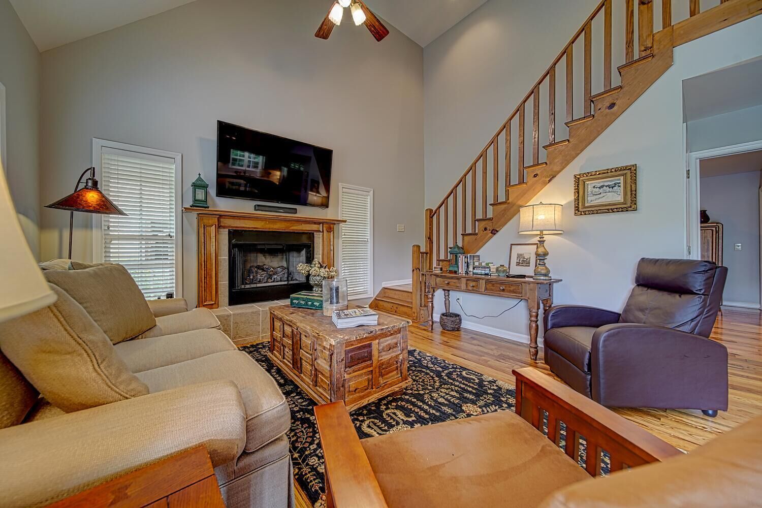 A living room with a fireplace, sofa, armchair, and a staircase.