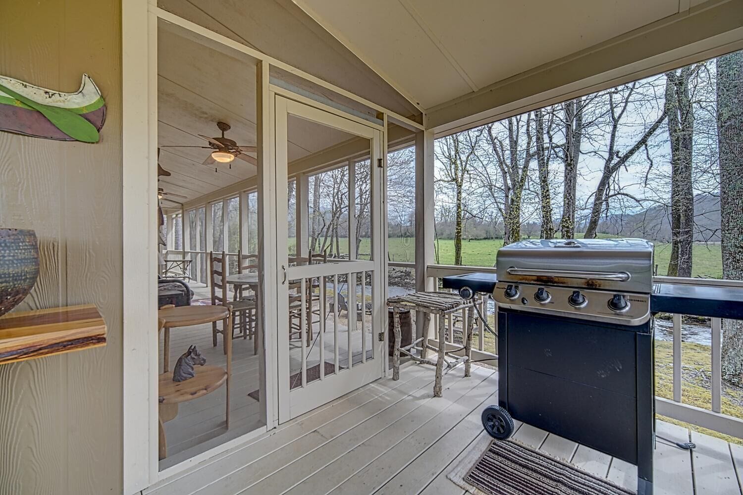 A covered outdoor area with a grill, dining tables, and chairs.