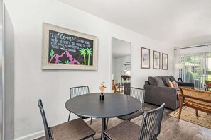 Un salon moderne avec une table ronde, des chaises, un canapé et un panneau d’accueil fixé au mur.