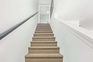 A staircase with a handrail, leading to a door at the top.