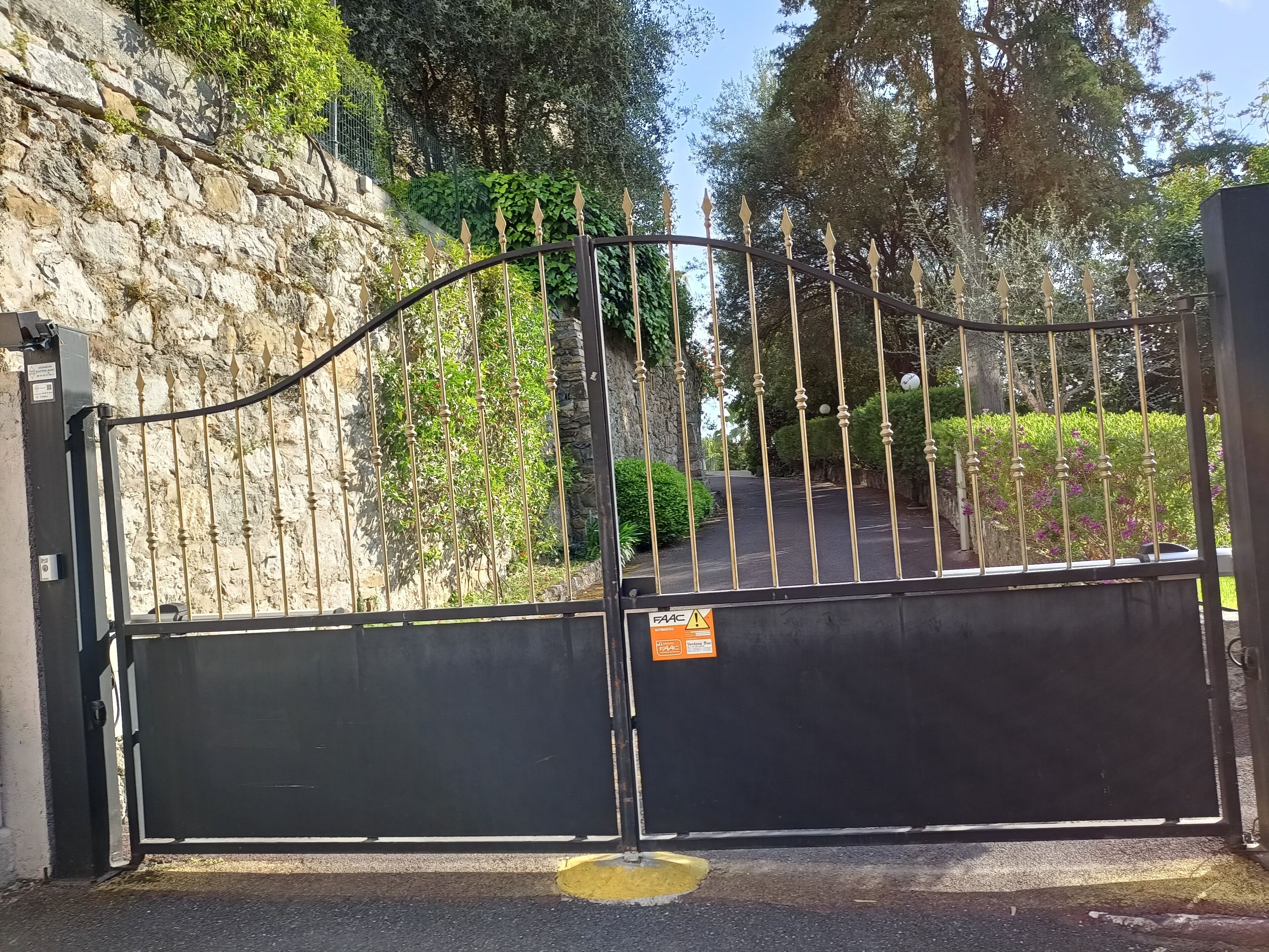 A gated entrance with a stone wall and a metal gate.