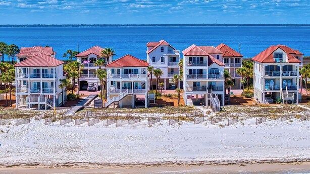 A beachfront hotel with multiple-story buildings, balconies, and a sandy beach. - Blue Heron - Dog Friendly, Community Pool, Across from Beach, Sunset Beach! (St. George Island)