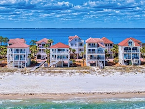 A beachfront hotel with multiple-story buildings, balconies, and a sandy beach.