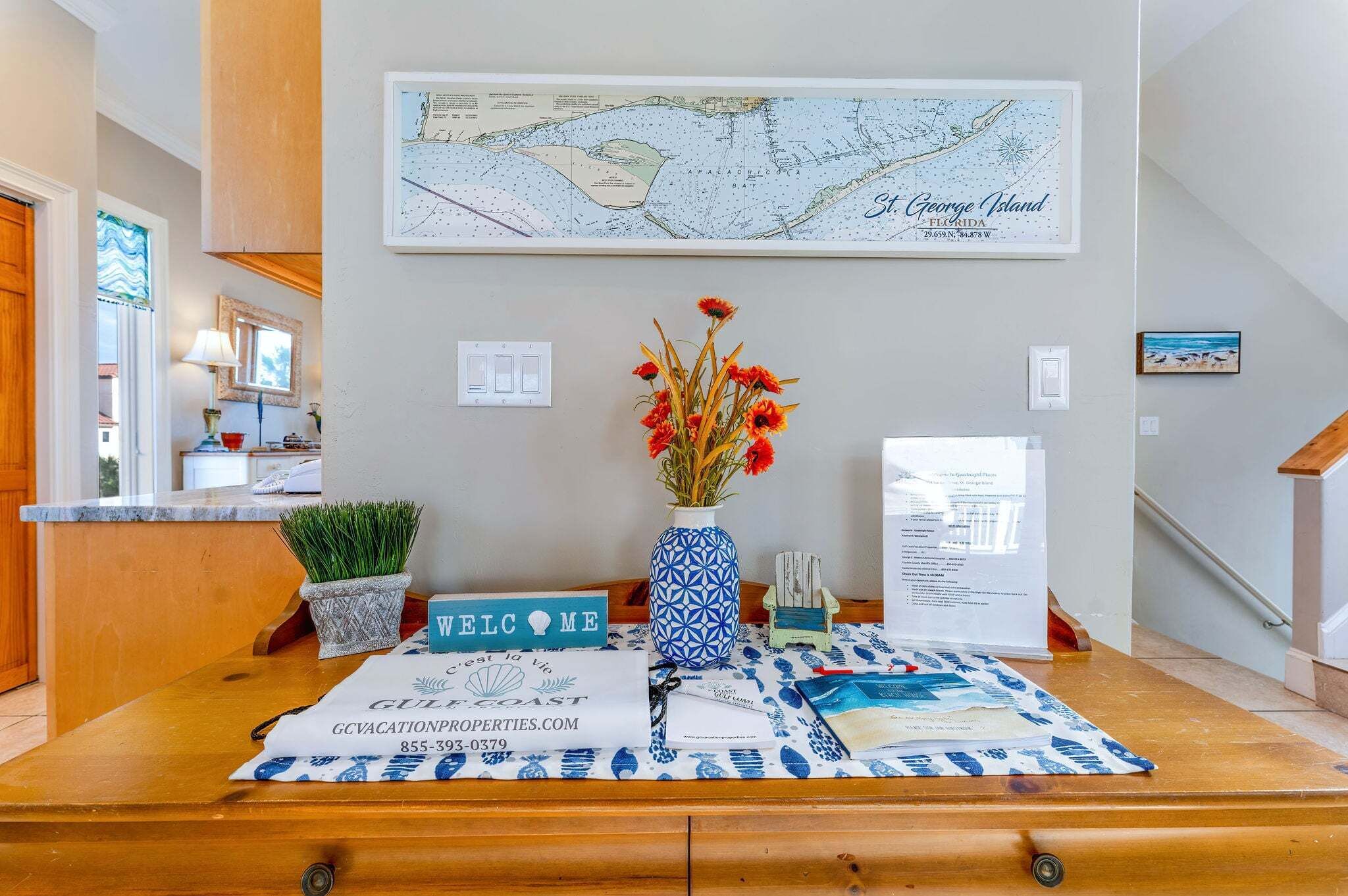 A reception desk with a welcome sign, a map of St. George Island, and a vase with red flowers.