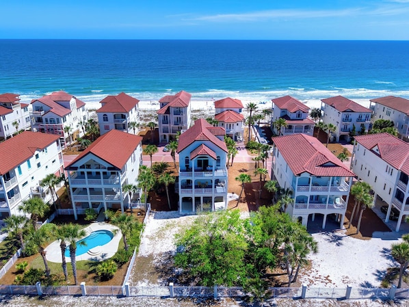 A coastal hotel with multiple buildings, a swimming pool, and a view of the ocean.