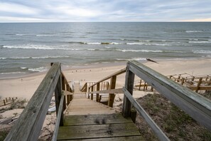 A wooden staircase leading to a sandy beach with the ocean in the background.