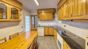 Eine Küche mit Holzausstattung, einer Granit Arbeitsplatte, einem eingebauten Herd und einem Essbereich mit Holztisch und Stühlen.