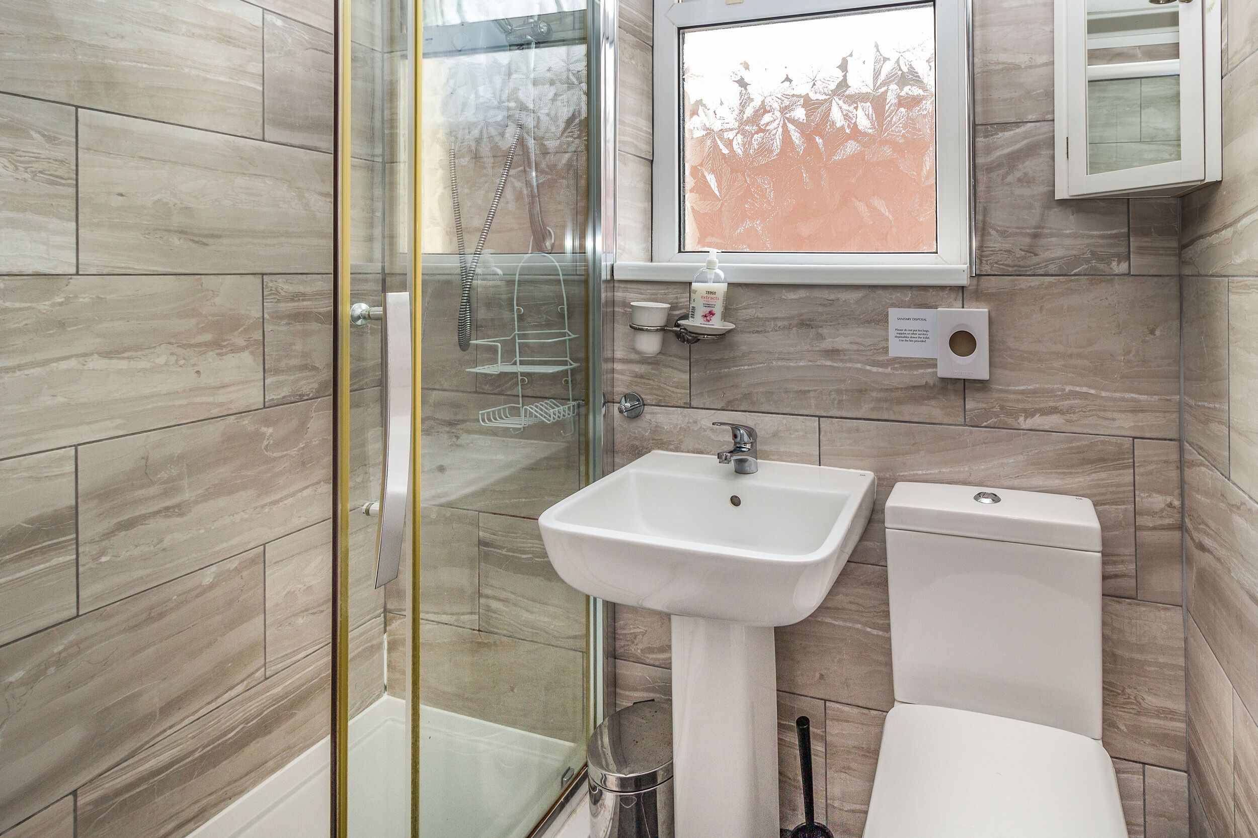 Ein Badezimmer mit Duschkabine, Standwaschbecken und Toilette.