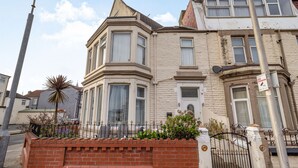 A corner building with a bay window, a brick wall, and a metal gate. - Cherry Tree House (Blackpool)