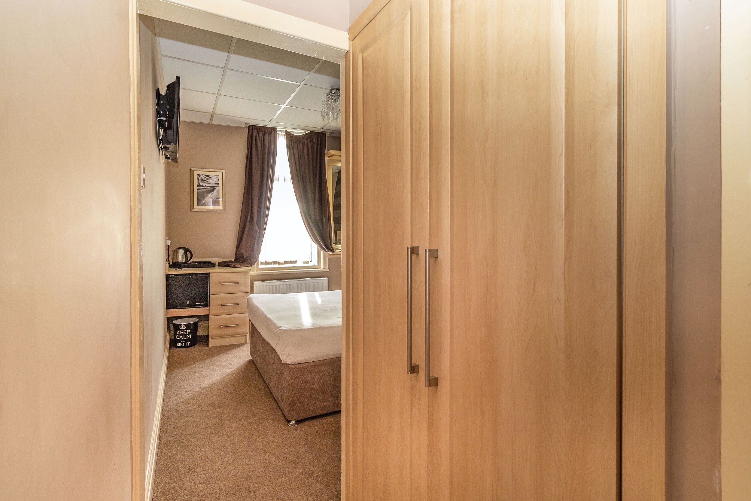 Une chambre à coucher avec un lit, un bureau, une armoire et un radiateur.