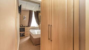 Une chambre à coucher avec un lit, un bureau, une armoire et un radiateur.