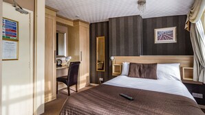 A hotel room with a large bed, a desk with a chair, a mirror, a picture on the wall, and a ceiling light fixture. - Cherry Tree House (Blackpool)