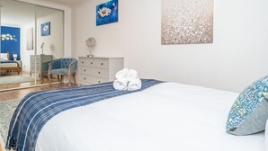 Un dormitorio con una cama grande, un aparador, una silla y un espejo.