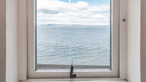 Una ventana con vistas al mar y un cielo nublado.