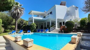 Un bâtiment moderne à deux étages, doté d’une piscine, de chaises longues bleues et d’un escalier menant à l’étage supérieur.