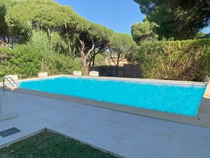 A rectangular swimming pool with a tiled deck surrounding it.