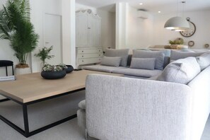 A modern living room with a sofa set, a coffee table, and a white wardrobe.