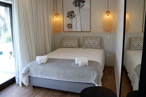 A bedroom with a bed, two wall-mounted lamps, a window with curtains, and a mirror.
