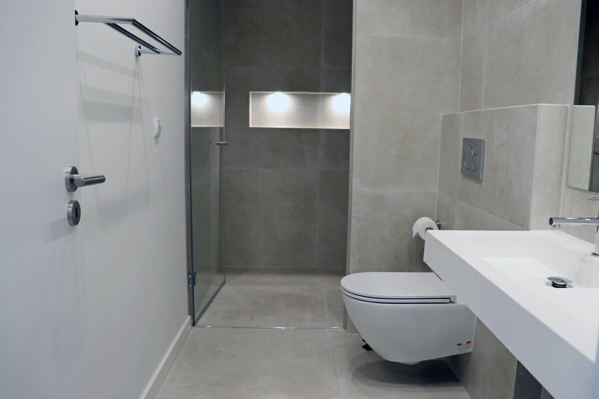 Une salle de bain moderne équipée de toilettes, d’un lavabo et d’une douche à parois en verre.