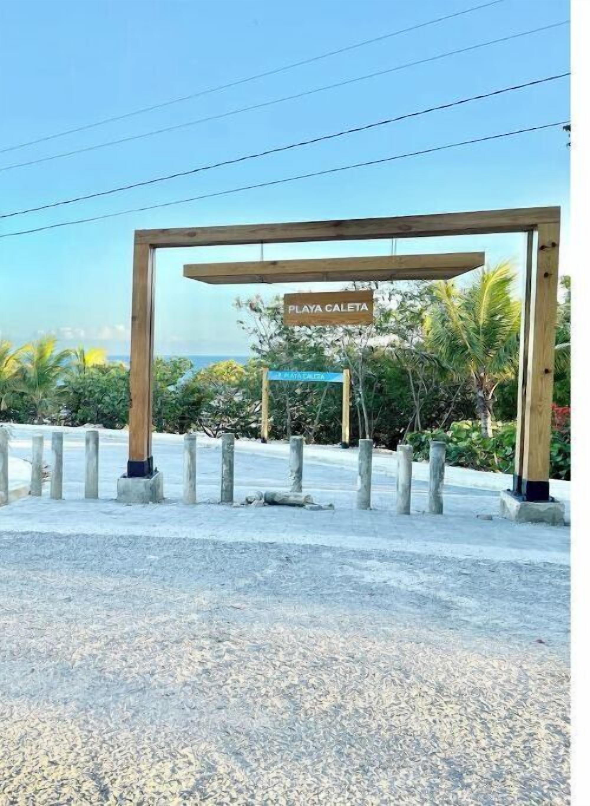 Una estructura de pergolat de fusta amb un rètol que diu "PLAYA CALETA".