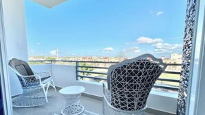 A balcony with two white wicker chairs and a small round table, overlooking a cityscape. - Apartment with 2BD, closed to the beach, Romana Airport & Altos de Chavón.  (La Romana)