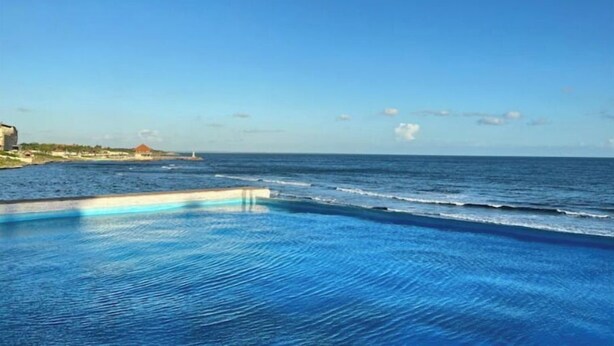 A clear view of a swimming pool with a view of the ocean and a lighthouse in the distance. - Apartment with 2BD, closed to the beach, Romana Airport & Altos de Chavón.  (La Romana)