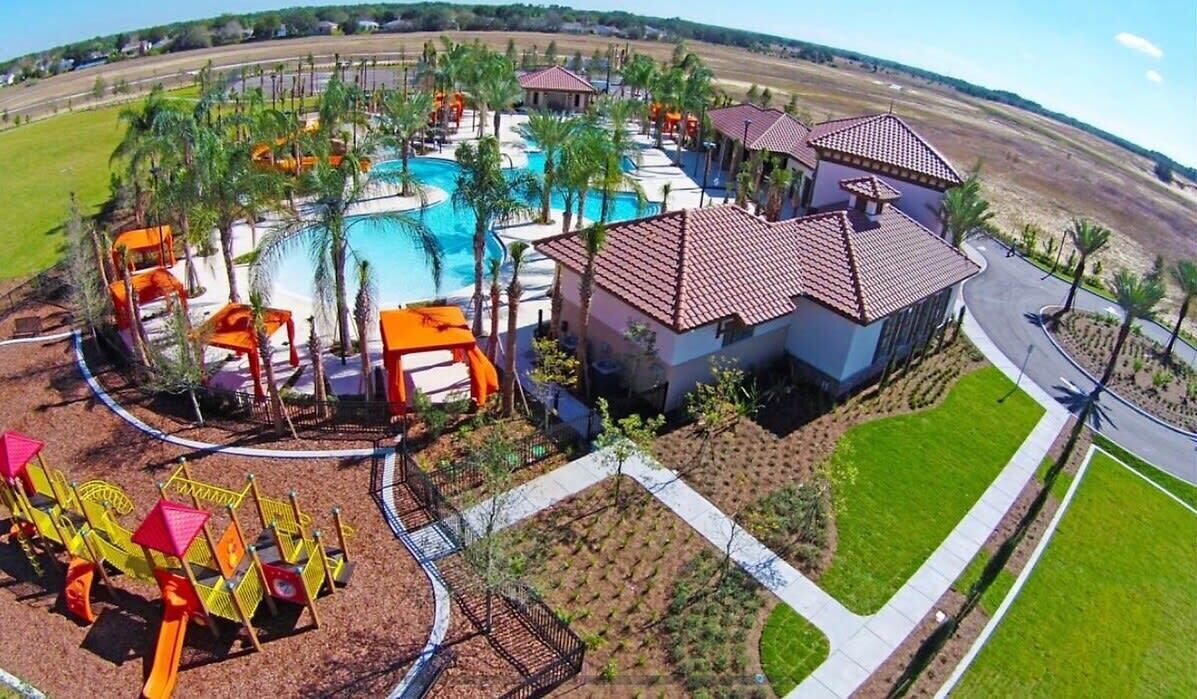 A resort with a swimming pool, palm trees, and a playground.