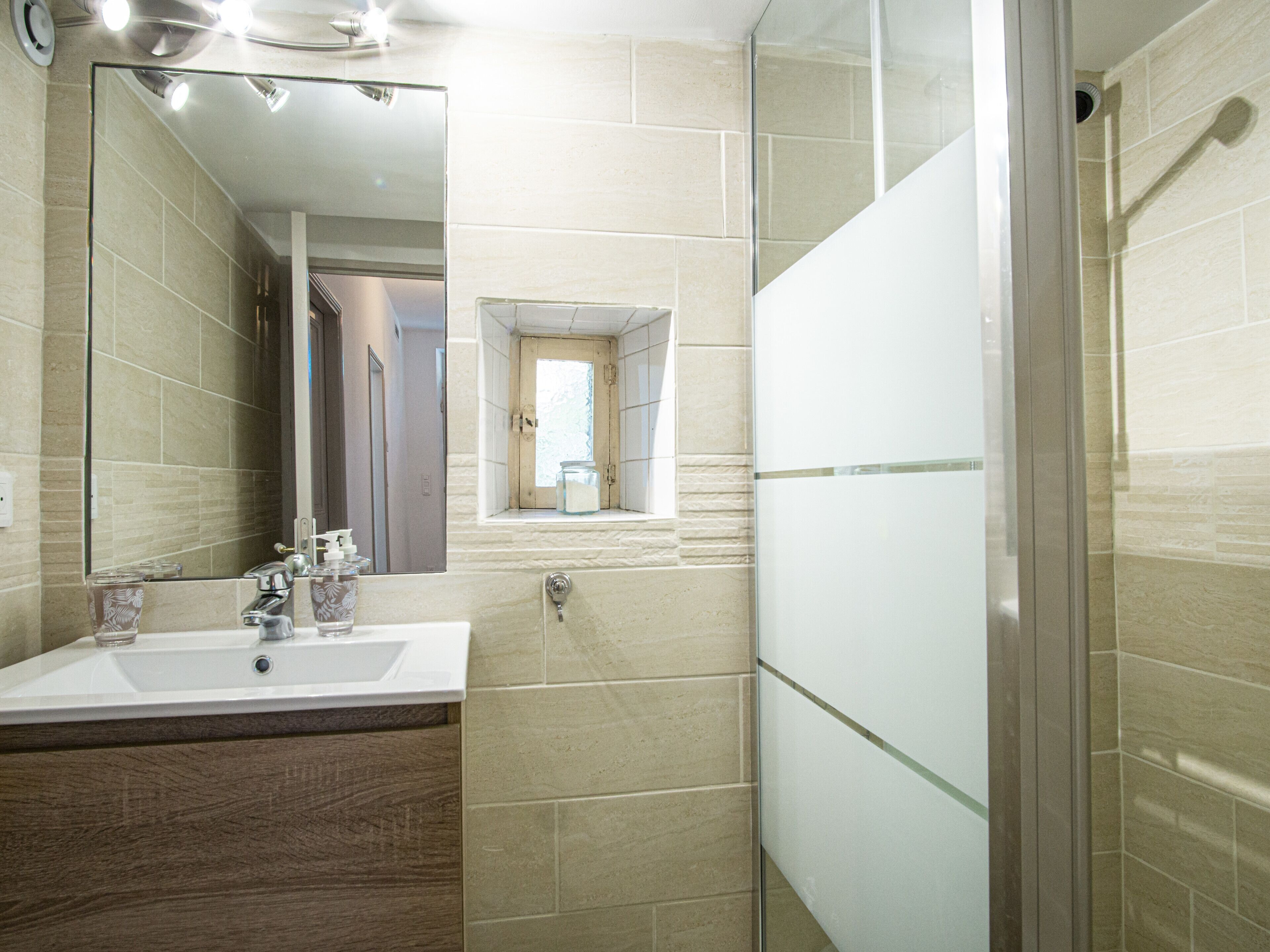 A modern bathroom with a large mirror, a sink, and a shower area.