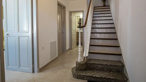 A hallway with a staircase, a door, and a wall-mounted light fixture.