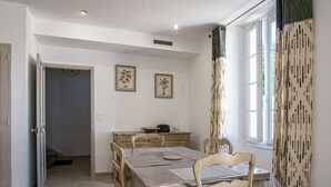A dining area with a table set for four, chairs, a small cabinet, and two framed pictures on the wall.