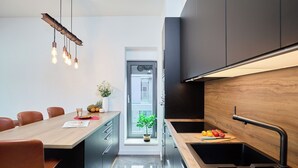A modern kitchen with a wooden island, black cabinets, and a stainless steel sink. - Hedera Estate, Hedera A15 (Dubrovnik)