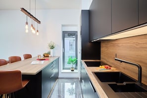 A modern kitchen with a wooden island, black cabinets, and a stainless steel sink. - Hedera Estate, Hedera A15 (Dubrovnik)