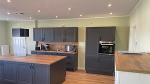 A modern kitchen with grey cabinets, a wooden island, and built-in appliances. - Apartment "Storage apartment" (Klein Upahl)