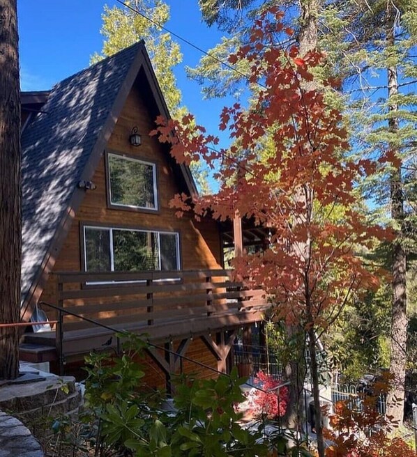 A cabin with a wooden exterior, a balcony, and a view of surrounding trees.