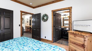 Une chambre à coucher comprenant un lit, une commode et un téléviseur affichant le message « BENNINGTON SUNRIVER VACATIONS ».
