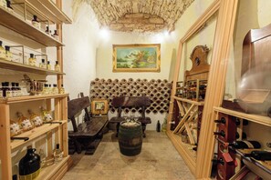 A room with wooden shelves, a barrel, a painting, and a wooden cabinet with wine bottles.