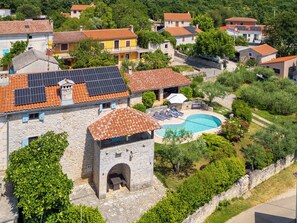 Un quartier résidentiel avec des bâtiments en pierre, une piscine et des panneaux solaires sur les toits.