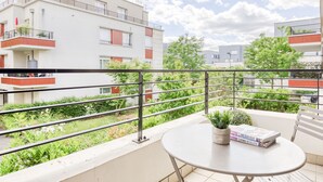 A balcony with a table, a potted plant, and a book. - Cosy Appt with Terrace 5 min. DISNEYLAND (Montévrain)