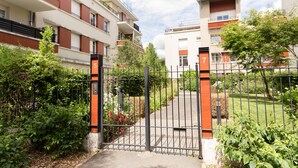 A gated entrance to a residential building with numbered apartment doors, surrounded by greenery and a well-maintained lawn. - Cosy Appt with Terrace 5 min. DISNEYLAND (Montévrain)