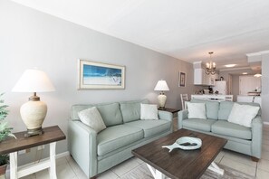 Uma sala de estar com dois sofás verde-claros, uma mesa de centro de madeira e um quadro na parede.