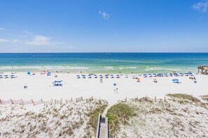 A beach with a wooden boardwalk leading to the shore, sandy beach, and umbrellas. - IS655- Beach Front, Park & Walk! Look at This View! Pool! (Gulf Shores)