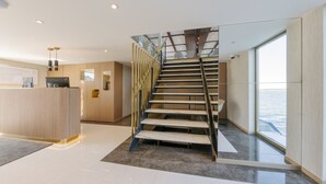 Un intérieur moderne comprenant un comptoir d’accueil, un escalier et une grande fenêtre donnant sur la mer.