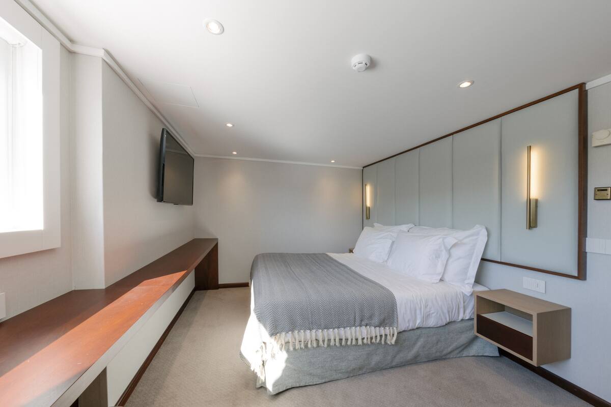 Un dormitorio moderno con cama, mesita de noche y un espejo grande.