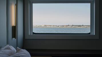 Ein Zimmer mit großem Fenster mit Blick auf ein Gewässer und eine entfernte Küste.