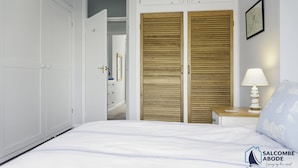 Un dormitorio con cama, armario de madera, mesita de noche con lámpara y un mapa enmarcado en la pared.
