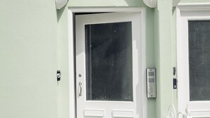 Una puerta blanca con mosquitero, un buzón y una placa con un número.
