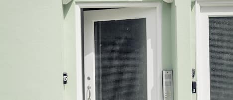 A white door with a mesh screen, a mailbox, and a number plate.