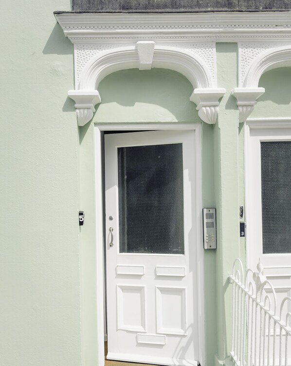 A white door with a mesh screen, a mailbox, and a number plate.